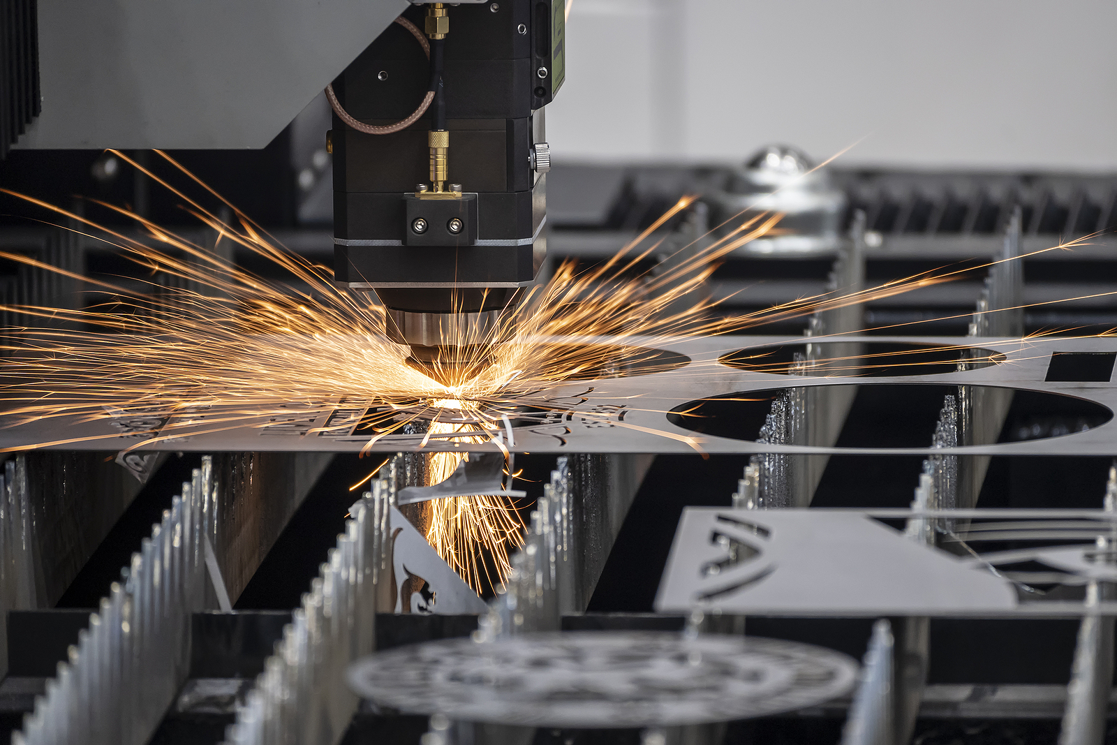 A CNC router cuts circular shapes in a thin sheet of metal.