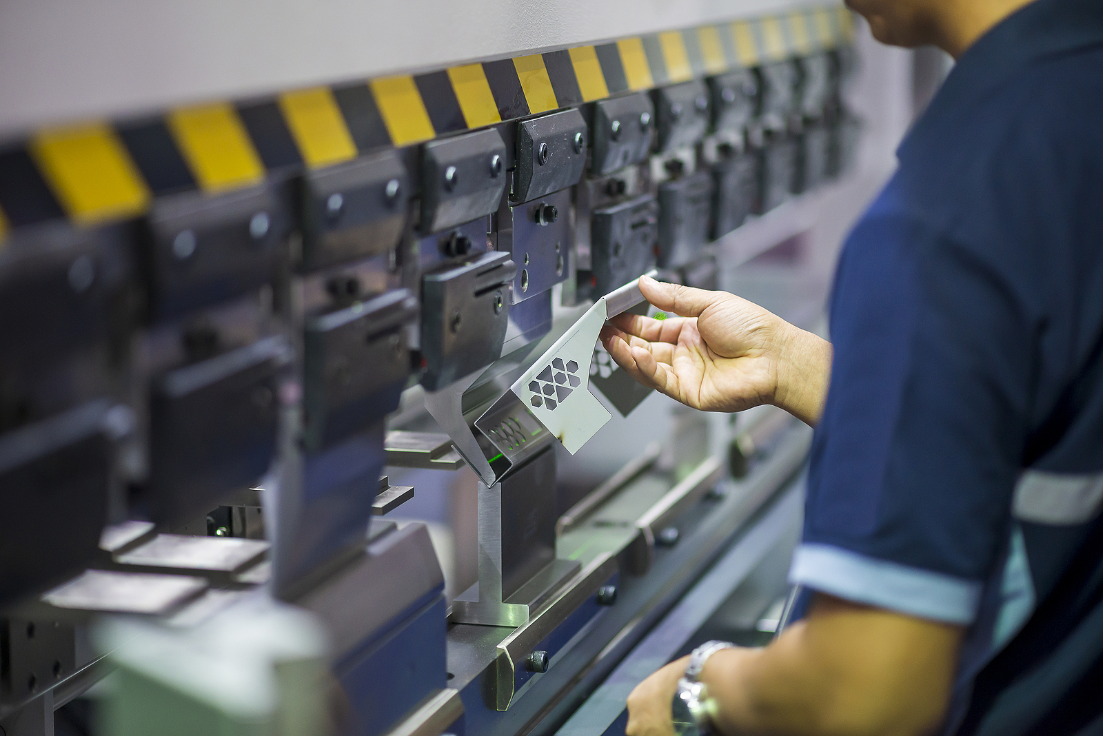 A technician operates a hydraulic machine to create a metal part.