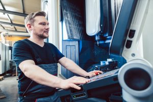 A machine operator programming a CNC lathe.