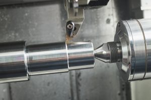 A CNC turning machine operating on a cylindrical metal workpiece.